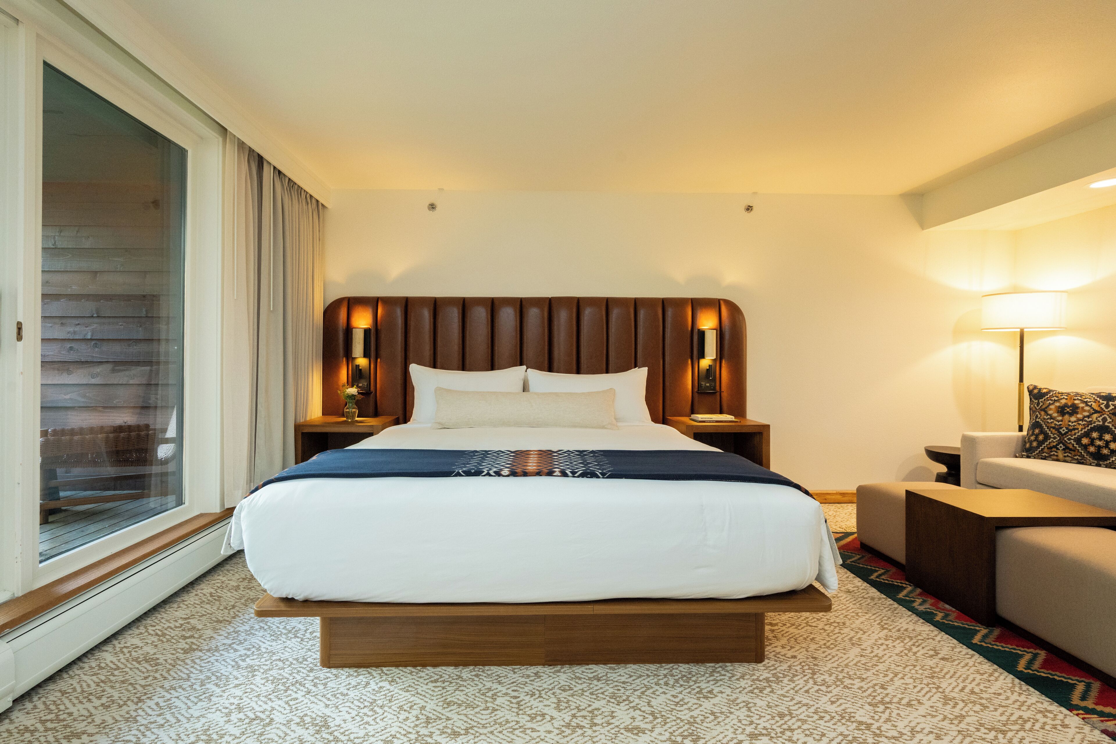 Een hotelkamer met een groot bed, een bank, een klein tafeltje en een lamp.