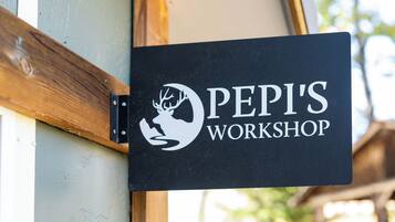 A sign for "PEPI'S WORKSHOP" with a logo, mounted on a wooden structure.