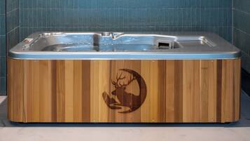 Un bain à remous en bois orné d’un logo représentant un cerf, installé devant un mur carrelé.
