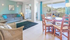 A living room with a sofa, a coffee table, and a dining area with wooden chairs and a table.