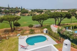 A pool area with a clear view of the surrounding landscape, including trees and distant buildings.