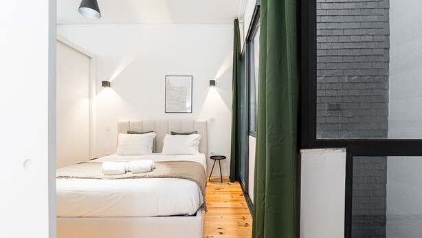A modern bedroom with a large bed, a bedside table, and a window with curtains. - GuestReady - A peaceful ambience in Porto (Porto)