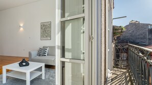 A modern living room with a grey sofa, a white coffee table, and a black vase. A framed botanical print is on the wall. - GuestReady - A peaceful ambience in Porto (Porto)