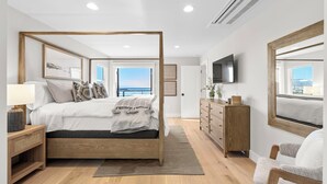 A bedroom with a four-poster bed, wooden nightstands, a dresser, and a chair.