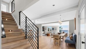 A spacious living area with a wooden staircase, a dining table, and a sofa.