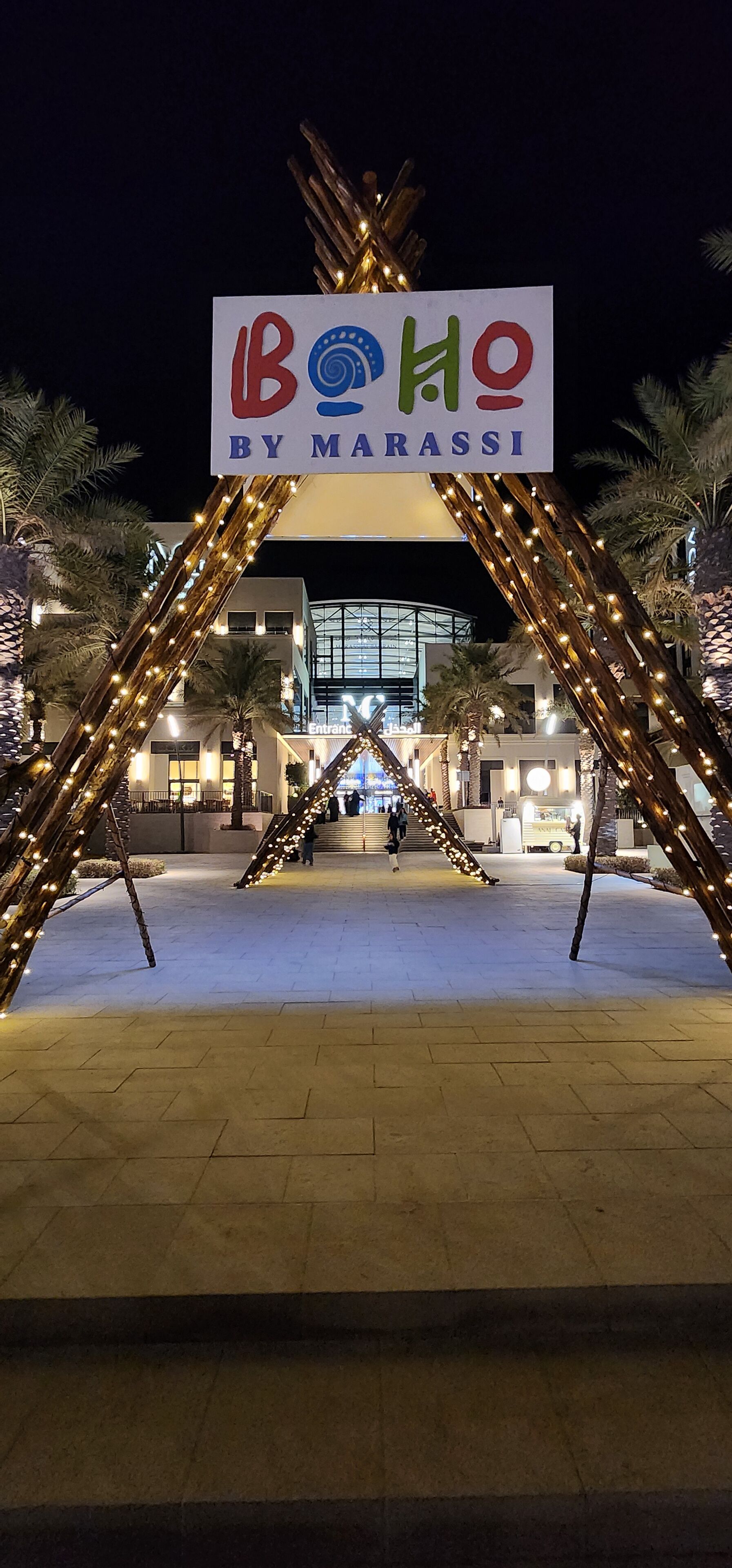 Entrada de un hotel con un letrero que dice "Bolo by Marassi" y un edificio moderno al fondo.