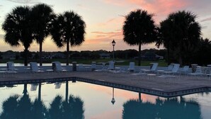 A poolside area with lounge chairs and palm trees at sunset. - Renovated! Between Two Squares with Golf Cart ! (The Villages)