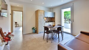 A modern kitchen with a dining area, a sofa, and a view of the outdoors. - Apho Apartment-Hotel (Rimini)