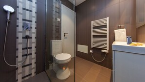 A modern bathroom with a shower, toilet, and a towel rack.