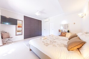 Ein modernes Schlafzimmer mit einem großen Bett, einem Kleiderschrank, einem Schreibtisch und einem Fernseher.