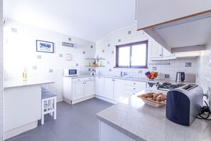 A modern kitchen with white cabinetry, a microwave, a sink, and a window.
