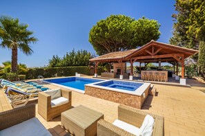 Un espace piscine avec des chaises longues et un coin salon abrité.