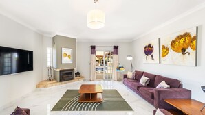 Una sala de estar moderna con chimenea, un televisor de pantalla plana grande y un conjunto de sofás.