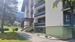 Un edificio de varios pisos con balcones, un vestíbulo cubierto y un jardín ajardinado.