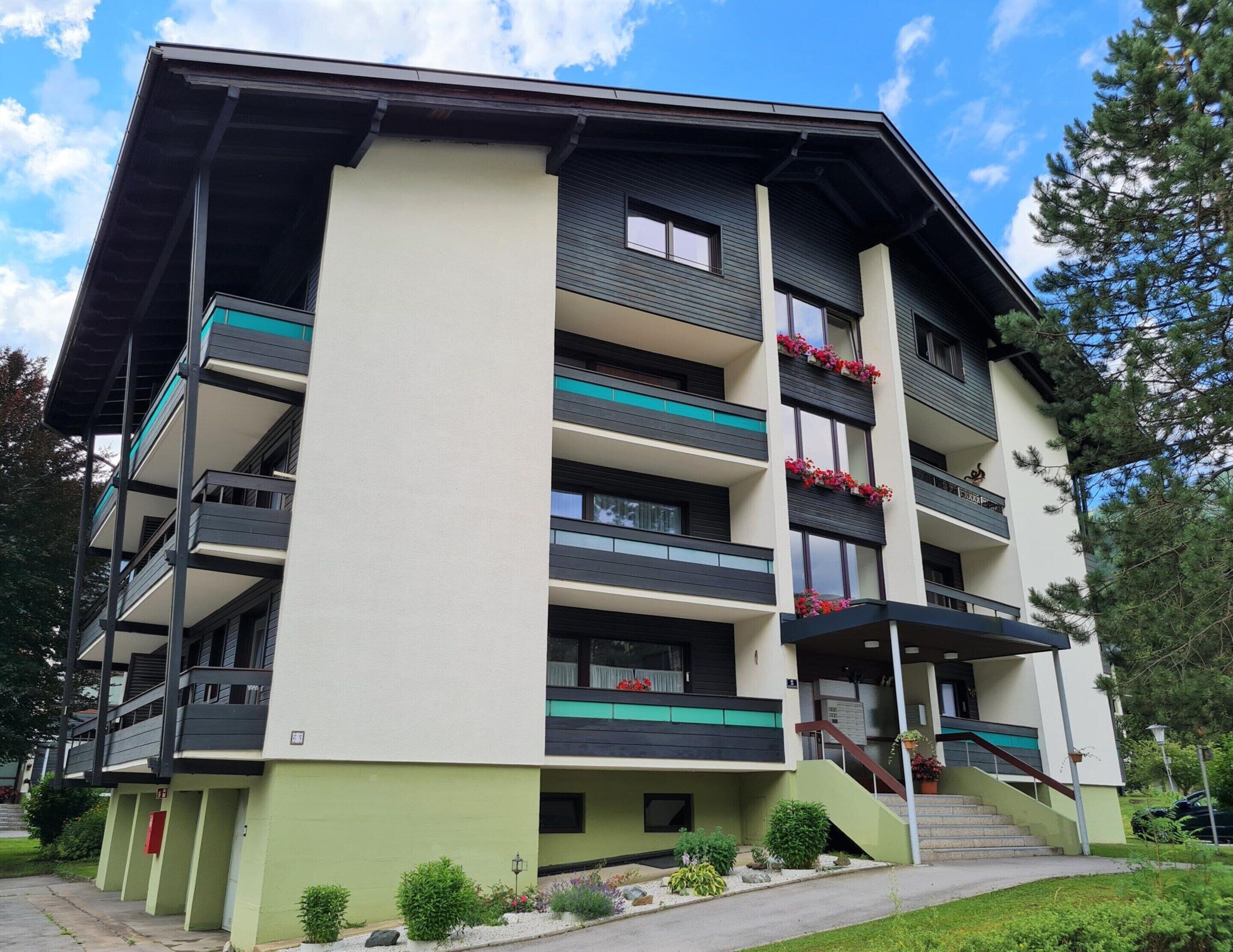 A multi-story building with balconies, a staircase, and a small garden area.