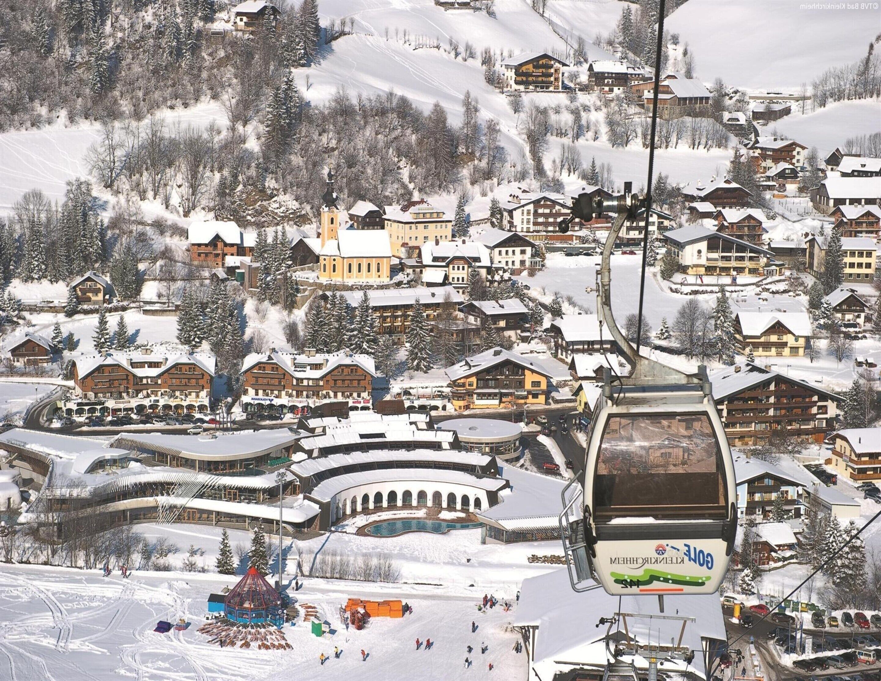 A snow-covered village with traditional wooden buildings, a ski lift, and a pool area.