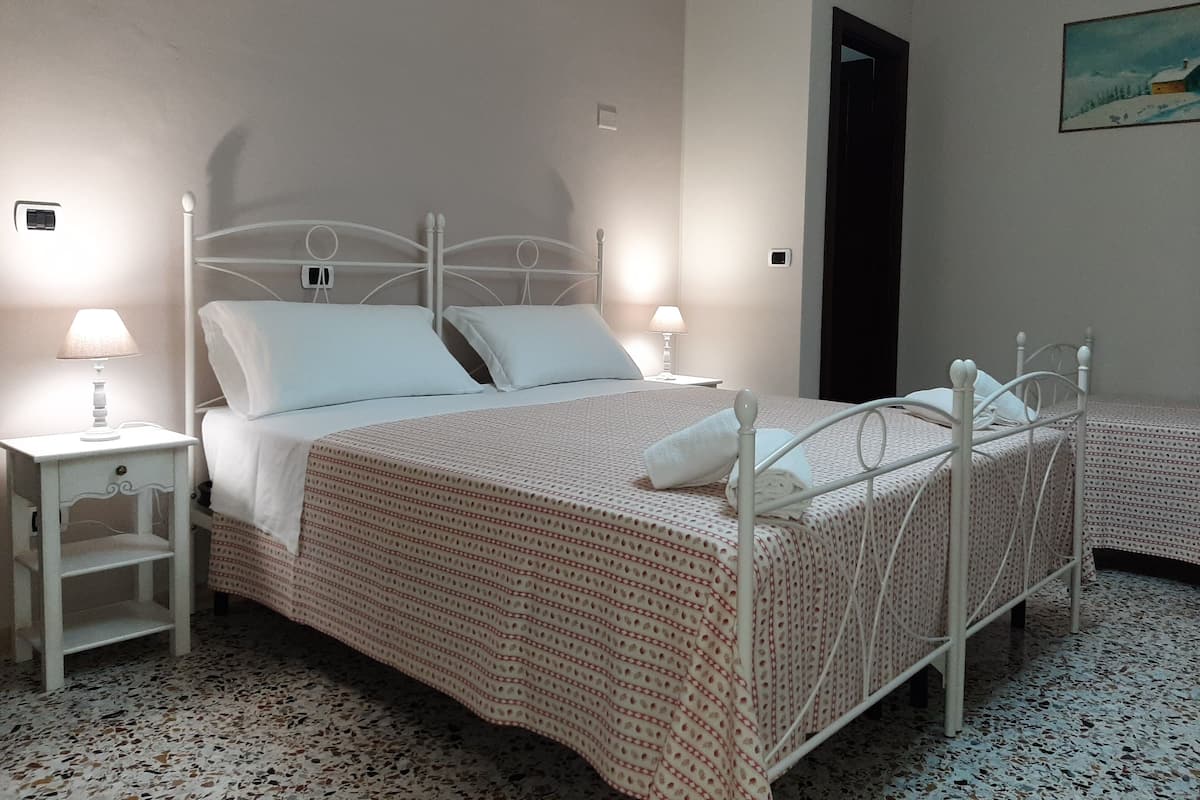 A bedroom with a bed, two bedside tables, and a painting on the wall.