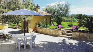 A patio area with a table and chairs, a stone wall, and a playground in the background. - Agriturismo Il Casolare Di Nonno Mario  (Manoppello)