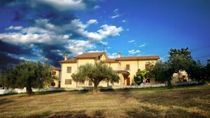 A two-story house with a tiled roof, surrounded by trees and a grassy yard. - Agriturismo Il Casolare Di Nonno Mario  (Manoppello)