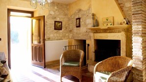 A room with a stone wall, a fireplace, wicker chairs, and a chandelier. - Agriturismo Il Casolare Di Nonno Mario  (Manoppello)