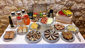 A table with various food items, including pastries, cheese, and fruits, set against a stone wall. - Agriturismo Il Casolare Di Nonno Mario  (Manoppello)