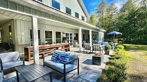 Eine überdachte Terrasse mit Gartenmöbeln, einem Esstisch und einem Garten mit einem Weg.