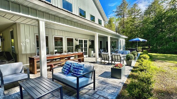 A covered patio with outdoor furniture, a dining table, and a garden area with a pathway.