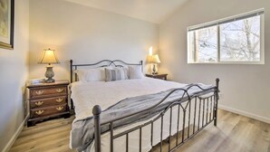 A bedroom with a bed, two bedside tables with lamps, a window, and a ceiling fan. - Cozy 2-bedroom house in Reno near UNR - Sleeps 7 (Reno)