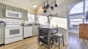 A compact kitchen with modern appliances, a dining area with a small table and chair, and a large window providing natural light. - Cozy 2-bedroom house in Reno near UNR - Sleeps 7 (Reno)