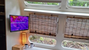 Un intérieur chaleureux avec une télévision, une table, une chaise et une fenêtre donnant sur un paysage verdoyant.