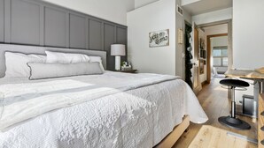 A bedroom with a large bed, a bedside table with a lamp, and a view of the dining area. - Perfectly Located 3 Bed 3.5 Bath Beautiful Townhome (Edwards)
