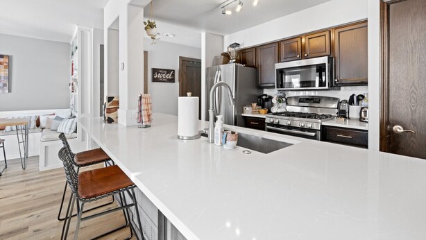 A modern kitchen with a large island, stainless steel appliances, and a dining area with a bench. - Perfectly Located 3 Bed 3.5 Bath Beautiful Townhome (Edwards)