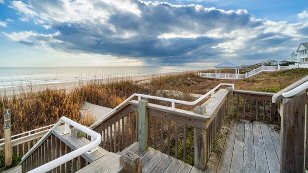 A wooden boardwalk leading to a beach with a cloudy sky. - Charming 5-bedroom oceanfront duplex with wonderful views (Emerald Isle)