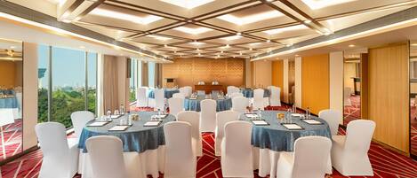 A conference room with round tables, white chairs, and a city view.