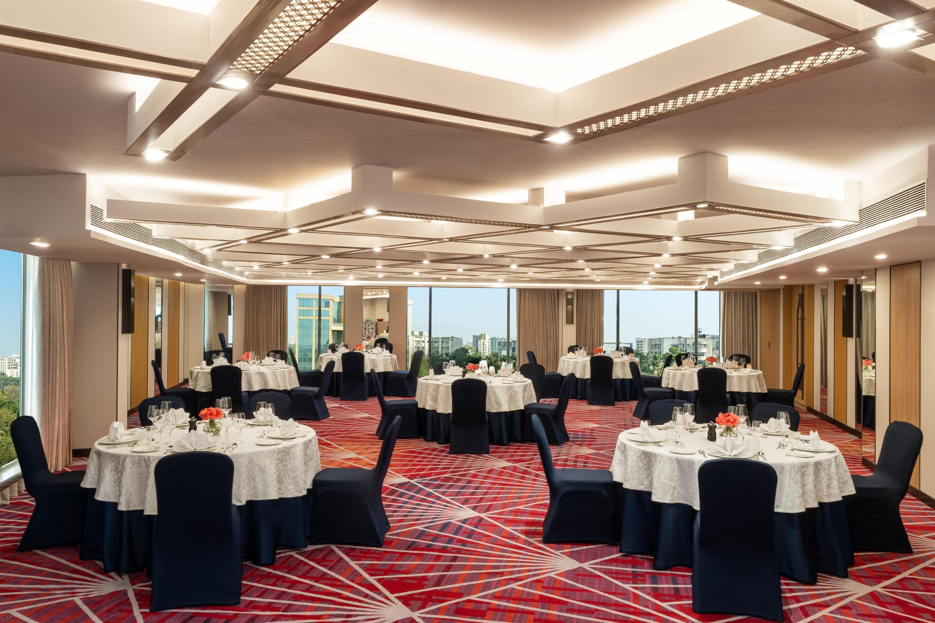 A conference room with multiple round tables, dark chairs, and a patterned carpet.
