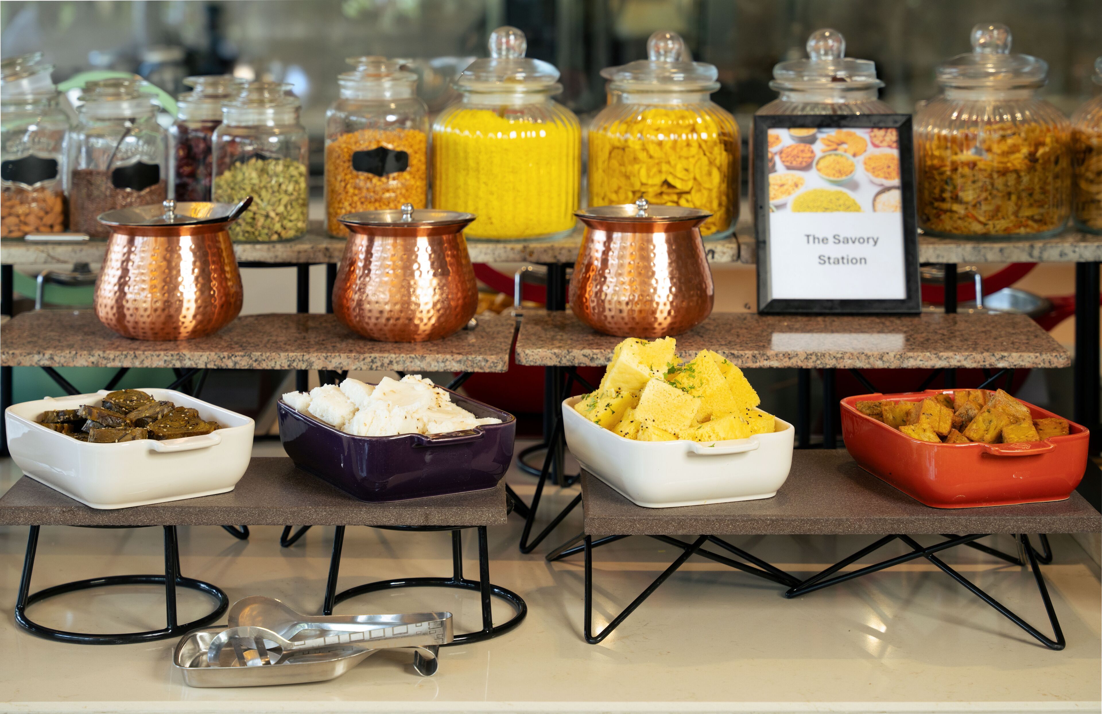 A buffet setup with various food containers and a sign labeled "The Savory Station".