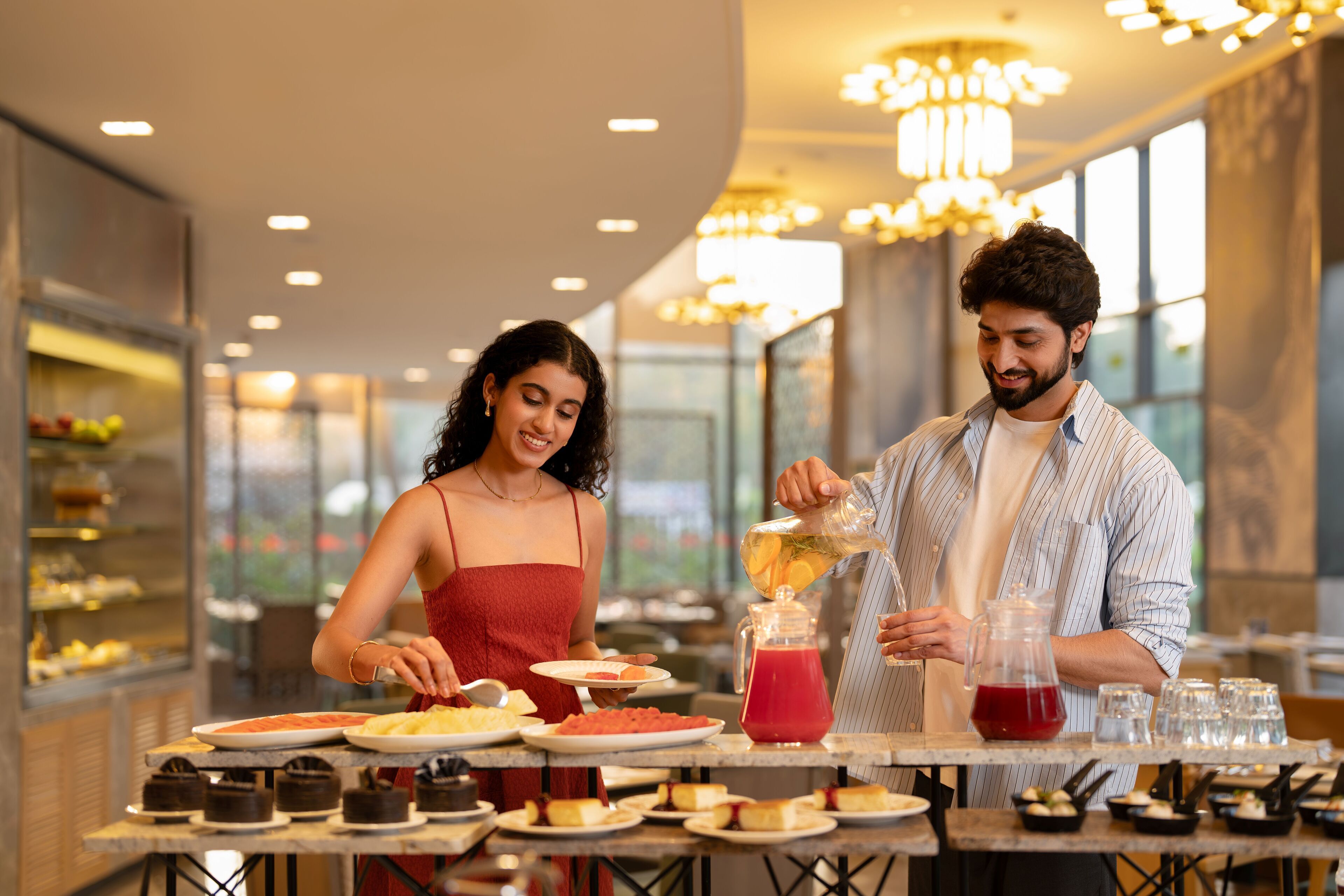 A couple dining at a restaurant with a variety of desserts and drinks on the table.