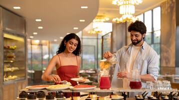A couple dining at a restaurant with a variety of desserts and drinks on the table.