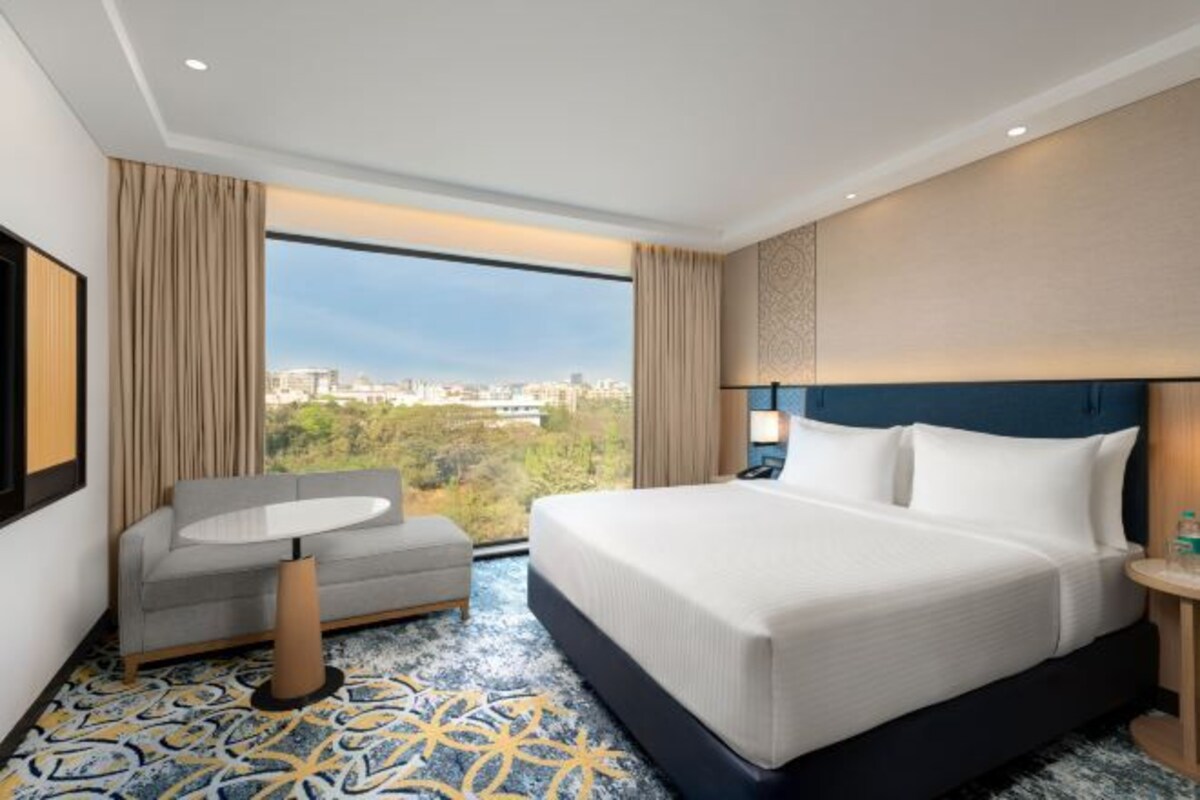 Una habitación de hotel con una cama grande, un sofá, una mesita y vistas a la ciudad.