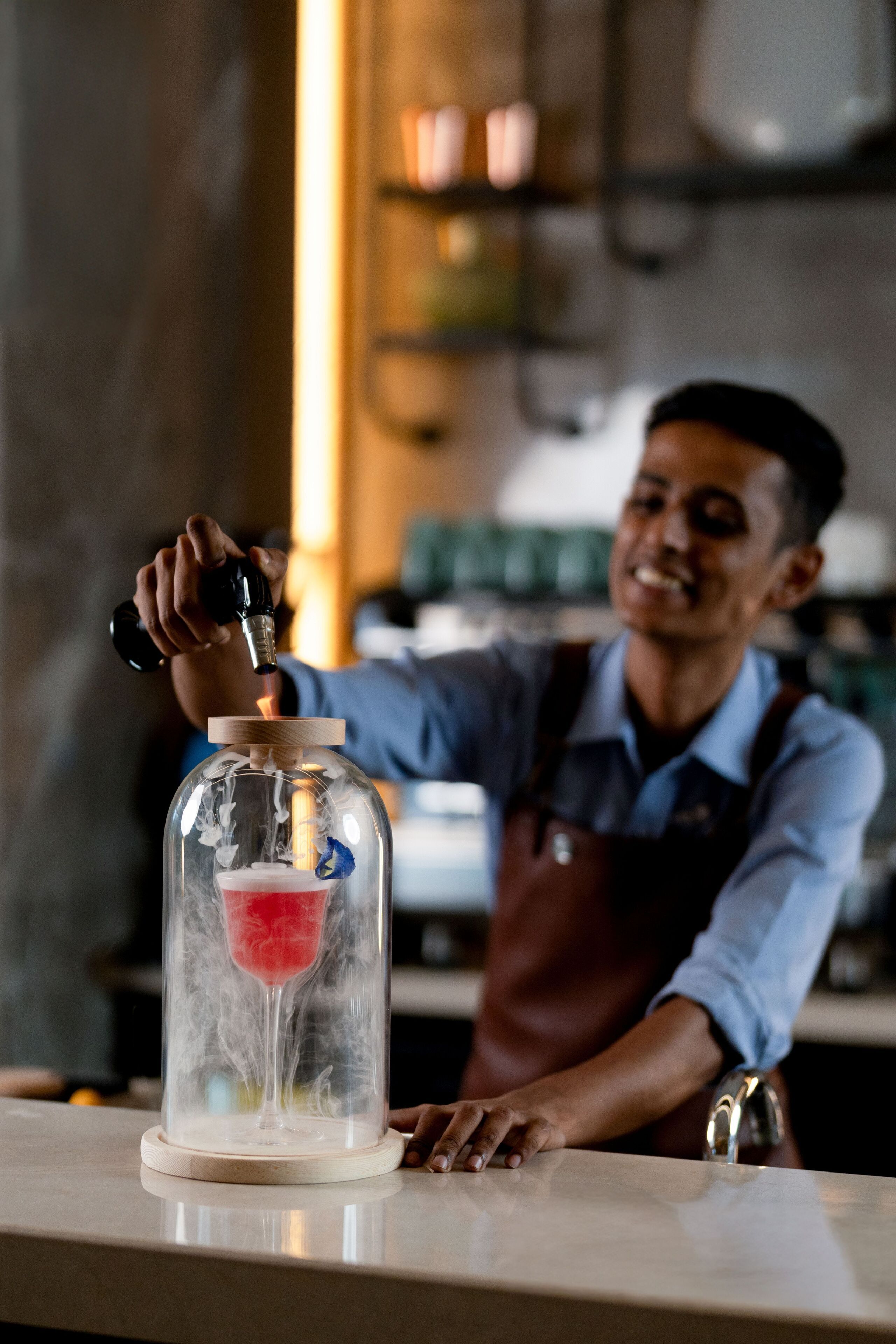 A person pouring a drink from a tap into a glass inside a transparent container.