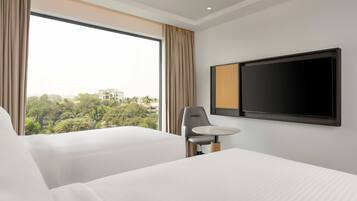 Une chambre d’hôtel avec deux lits, une télévision et une fenêtre avec des rideaux.
