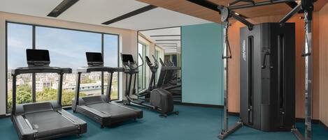 A modern gym with treadmills, elliptical machines, and a weightlifting station.