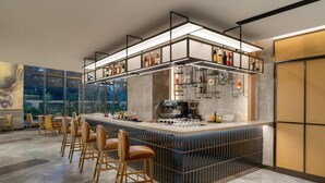 Uma área de bar moderna com balcão, banquetas e prateleiras cheias de garrafas.
