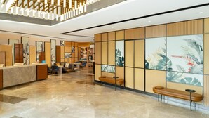 Um lobby moderno com balcão de recepção, área de estar e painéis decorativos.
