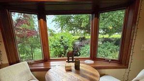 A corner seating area with a round wooden table, two chairs, and a view of greenery outside. - Beaufiul Sonoma house on large property in vineyards with lots of amenities! (Sonoma)