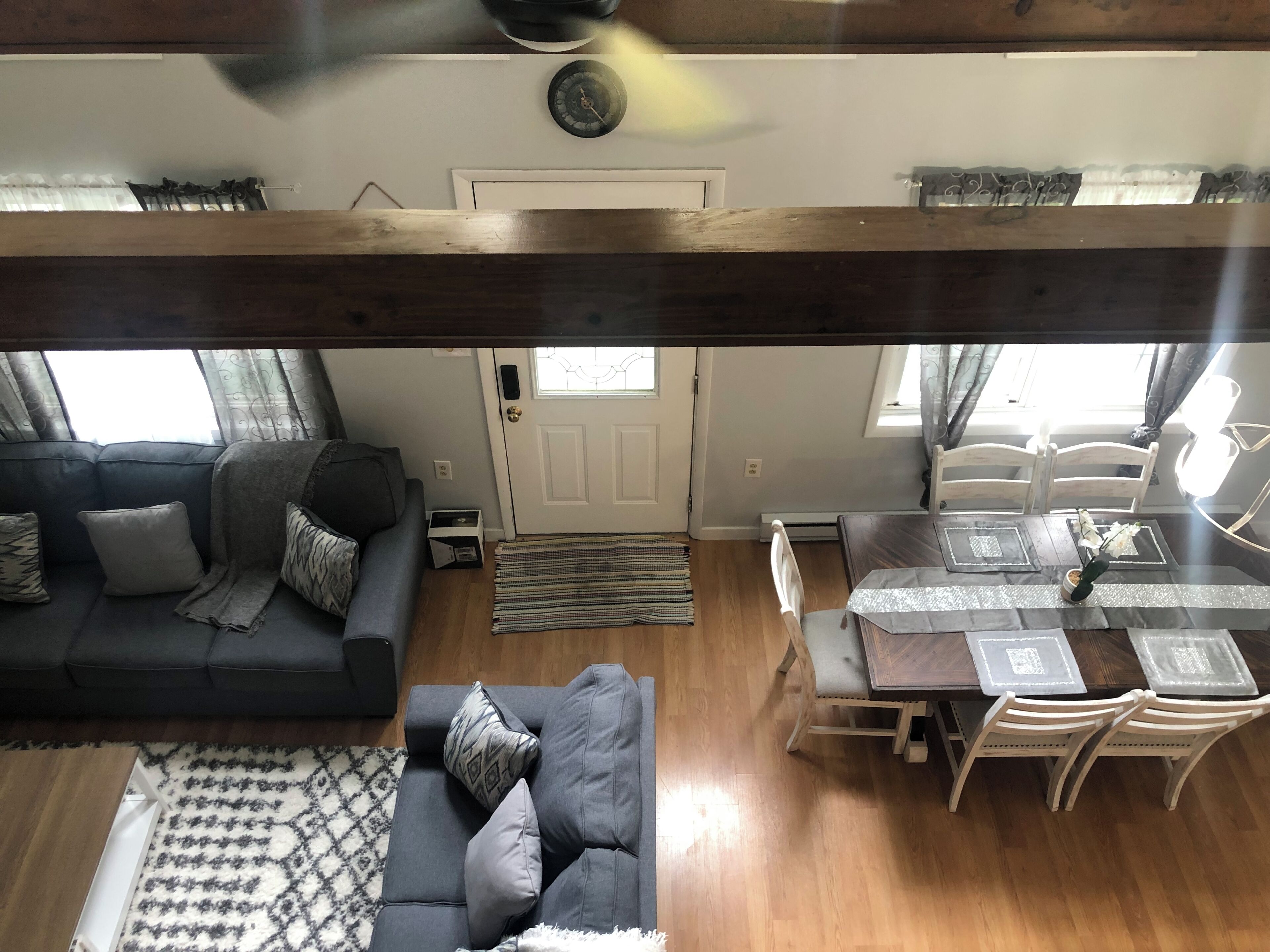 A cozy living room with a sofa, a dining table with chairs, and a wooden ceiling beam.