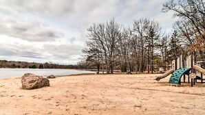 A sandy beach with a playground and trees in the background.