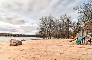 Ein Sandstrand mit Spielplatz und Bäumen im Hintergrund.