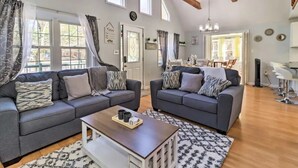 Un salon spacieux avec deux canapés gris, une table basse en bois et un coin repas comprenant une table et des chaises.