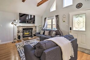 A living room with a stone fireplace, a flat-screen TV, a sofa, and a patterned rug. - Charming 3-bedroom Poconos Family Getaway in Albrightsville PA (Albrightsville)